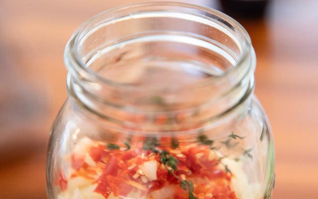 A glass jar filled with fire cider ingredients.