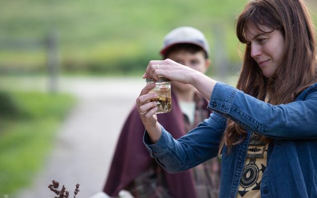 A participant hand tightens a ring lid onto a glass jar filled with chopped up roots and a clear liquid – the makings of a bitter tonic.