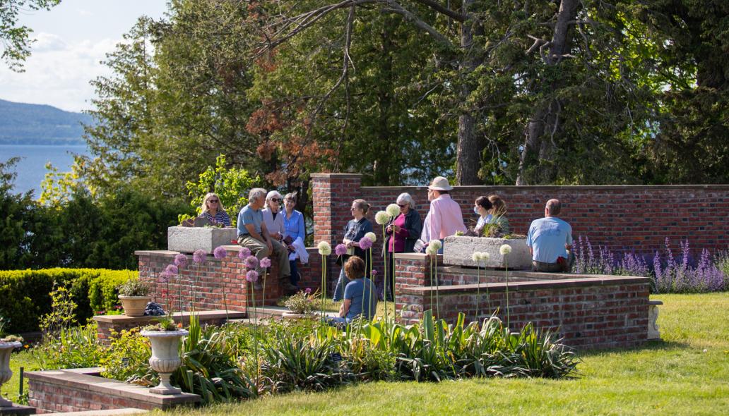 A group gathers along low brick walls surrounding the flower gardens at the Shelburne Farms Inn.