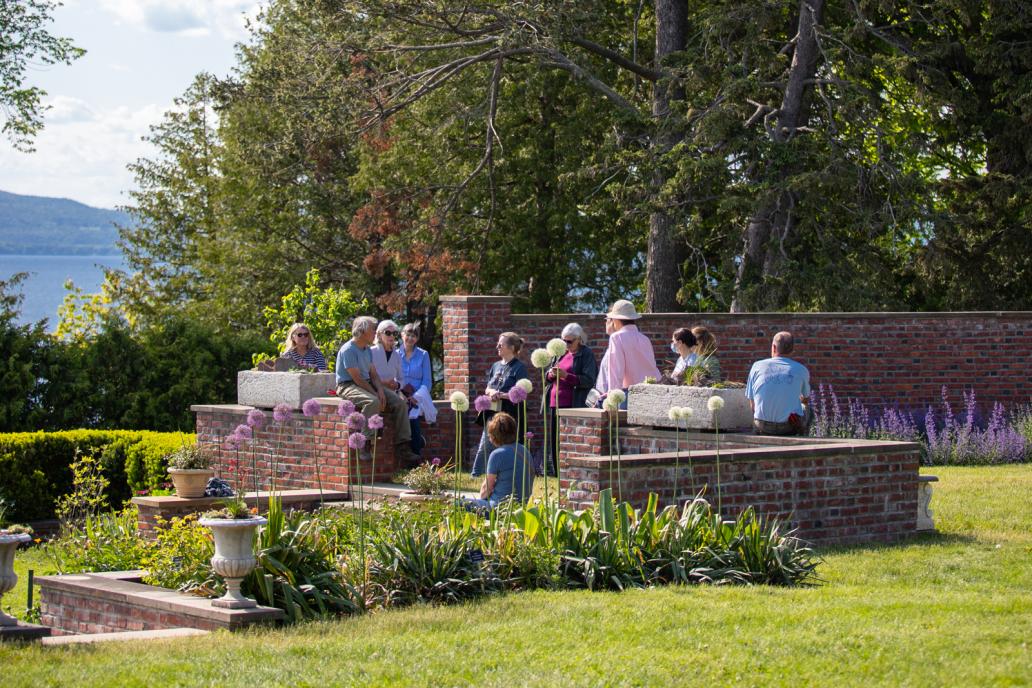 A group gathers along low brick walls surrounding the flower gardens at the Shelburne Farms Inn.