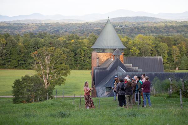 small group of people gathered on hill looking back towards Farm Barn tower and Green mountains