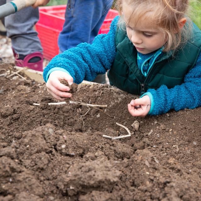 child digging in garden soil