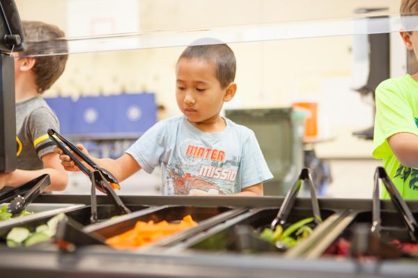 A young student selects fresh vegetables from a school salad bar. Photo by Ben Hudson.