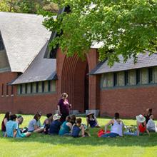 Educators sit in circle in front of Coach Barn at Shelburne Farms in summertime