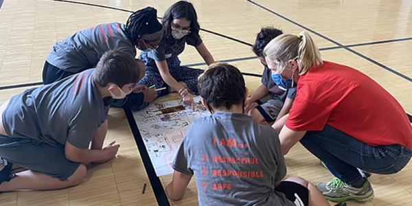 Students gather around poster on the floor