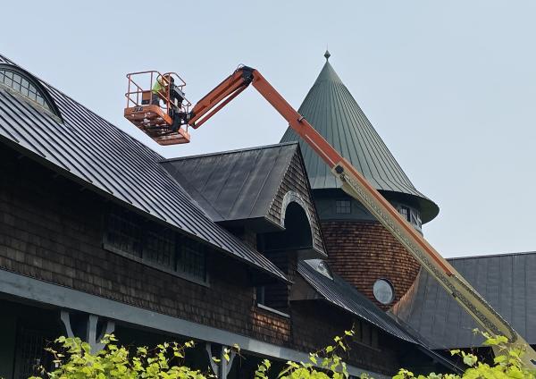 A worker in a lift installing lightning rods on Farm Barn roof.