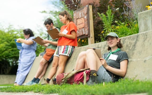 Educators sit outdoors, reading and writing
