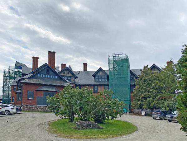 The inn with two sets of scaffolding and protective cloth wrap for working on two different chimneys