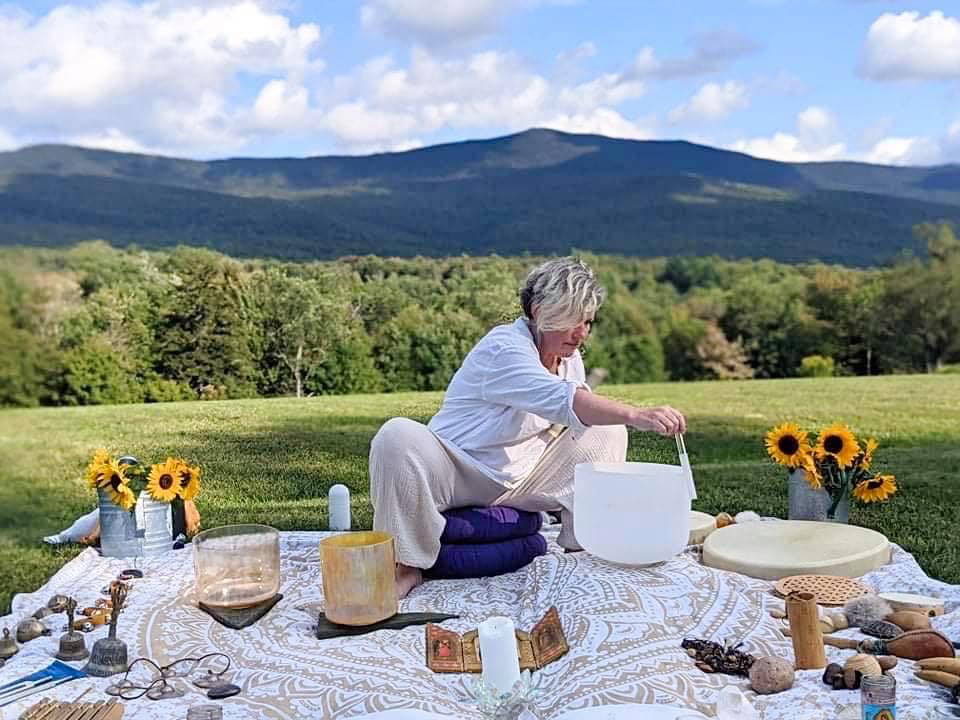 Melinda Kinzie with sound healing equipment outdoors.